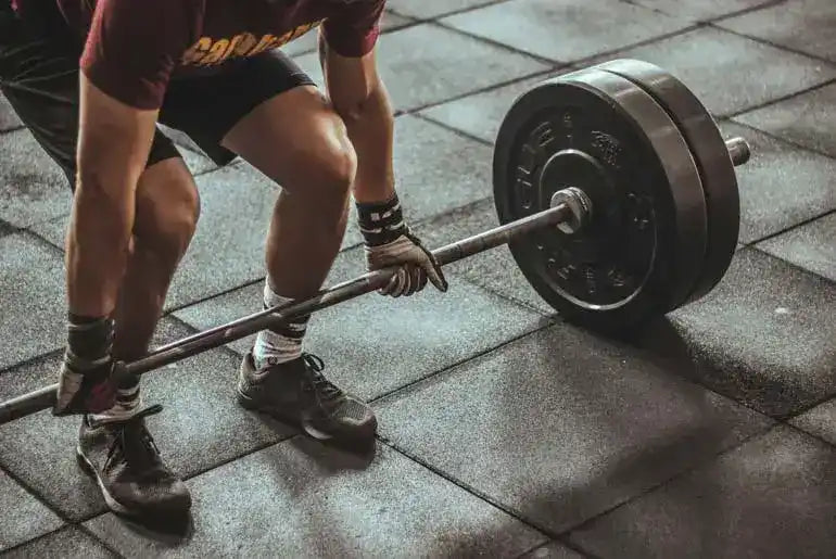 Loaded barbell with weight plates resting on a floor.