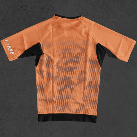 Short sleeve brown BJJ rash guard with hexagon camouflage from CYPHR Codebreaker Series, shown on a gray background.